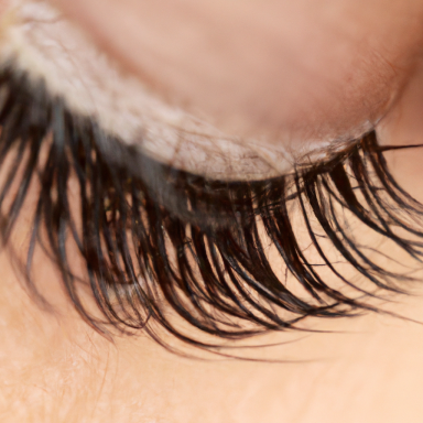 Nahaufnahme von langen, geschwungenen Wimpern auf einer Hautoberfläche.